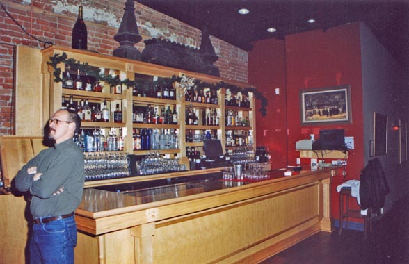 Chris standing at the bar of Matties House of
                Mirrors